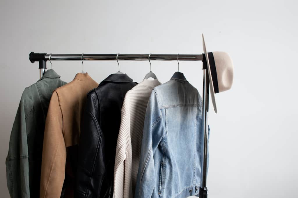 Men's jackets and a hat hanging on a metal clothing rack